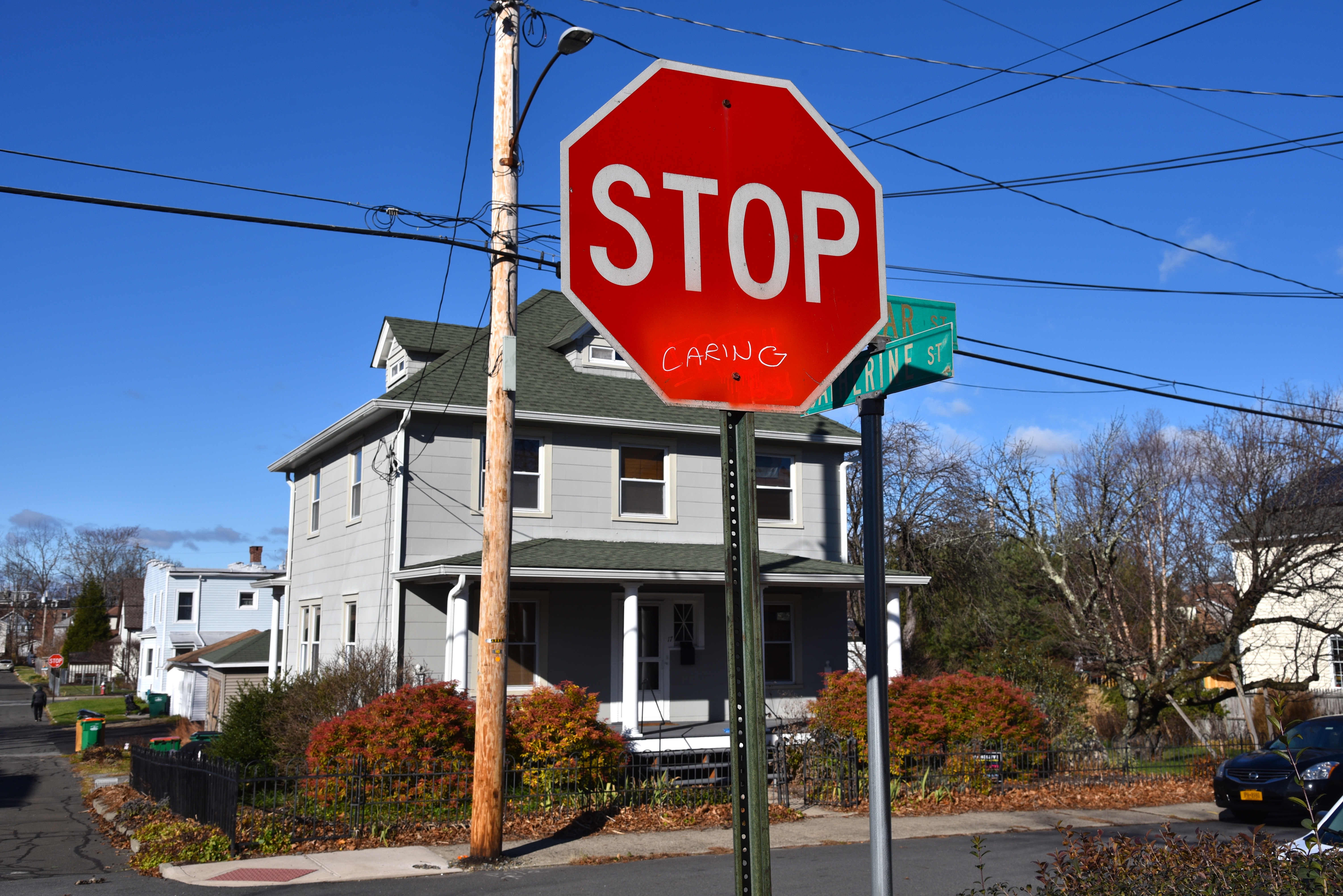 Stop sign with hand-written 'caring' under the word stop.